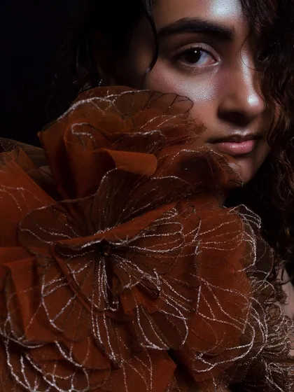 A detailed portrait showing the subtle, glossy finish on the lips and the highlight on the skin. The hair is styled with a natural, wet-curl texture.
