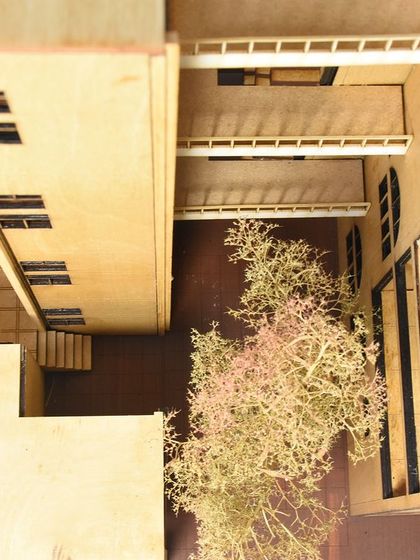 An overhead view of a wooden architectural model, showing the relationship between buildings and a central courtyard with a tree. Models allow us to understand the feel of a space.