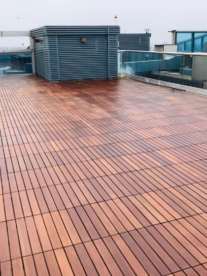 This wide shot shows the scale of a large rooftop terrace decked entirely in IPE wood tiles. The consistent grain and rich color elevate the entire outdoor area.