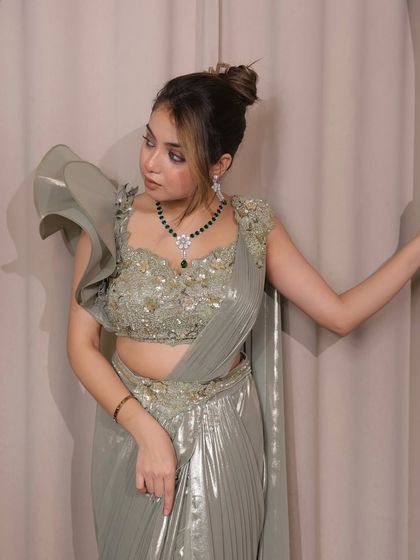 A full view of the sage green saree, showing how the pleated metallic fabric flows gracefully. It’s a perfect fusion of tradition and modern sophistication.
