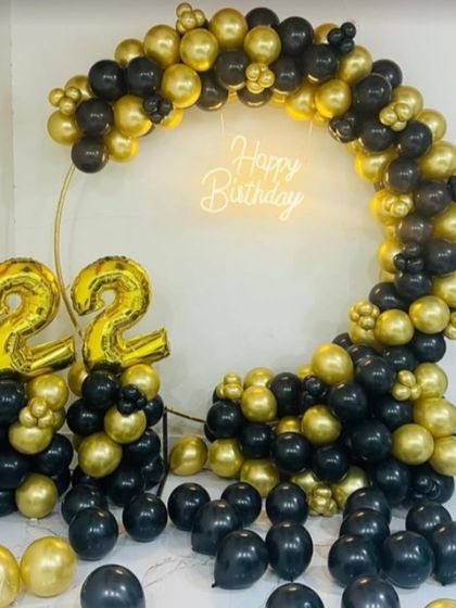 A classic and bold black and gold theme for a 22nd birthday. The full circular balloon arch frames the neon sign, and large foil number balloons clearly show the milestone age.