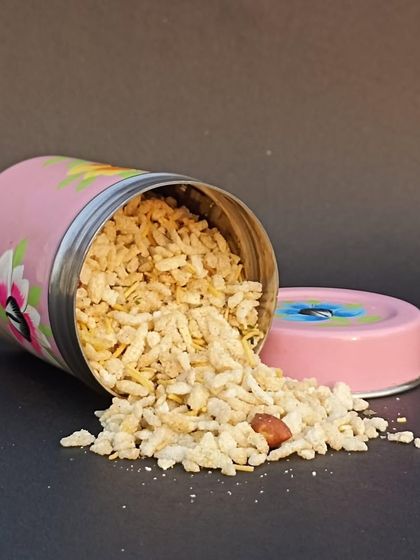 A hand-painted pink tin with snacks spilling out, part of a beautiful collection of painted vessels perfect for adding art to your home.