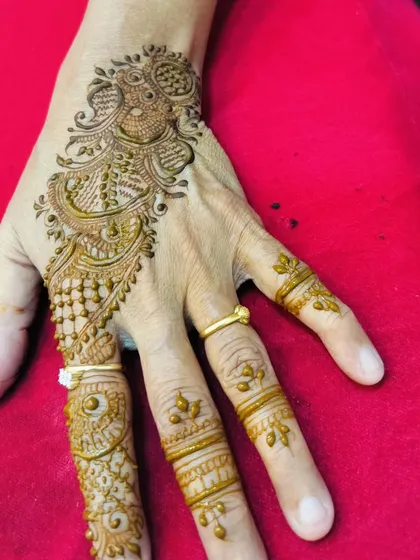 A single peacock motif on the back of the hand. This is a classic and graceful design, perfect for any celebration.