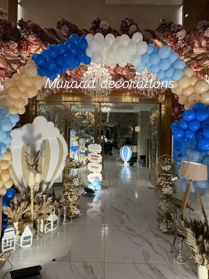 Welcome your baby home with a spectacular hot air balloon themed entrance. This grand archway, decorated in shades of blue, white, and beige, creates a magical passage into the celebration hall for a memorable Mundan or welcome party.