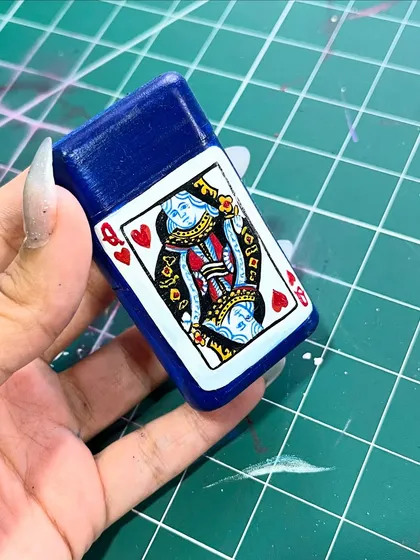 A tiny masterpiece. I hand-painted a Queen of Hearts playing card onto this blue lighter case.