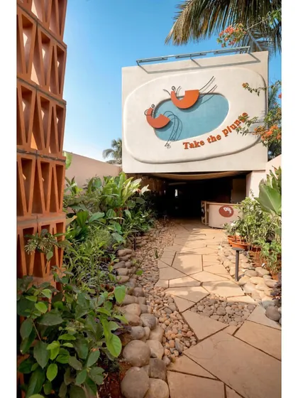 The entrance signage for Dubki, "Take the Plunge," is set against a backdrop of lush greenery and a terracotta brick jaali wall. This entry sequence immediately establishes the project's playful and nature-inspired theme.