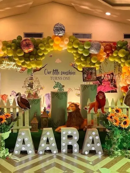This "Our Little Sunshine" jungle-themed first birthday combines cute animal props with a bright and cheerful balloon garland. The marquee letters for the name add a personalized, glowing touch.