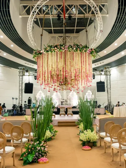 Setting the stage for a grand celebration. This wide shot captures the magnificent scale of the wedding decor, from the floral chandelier to the beautifully arranged aisle.