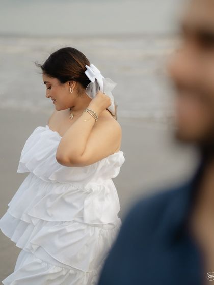 A beautiful, soft-focus portrait of the bride on the beach. The focus on her gentle expression and the windswept hair creates a dreamy and romantic feel, perfect for a coastal pre-wedding session.