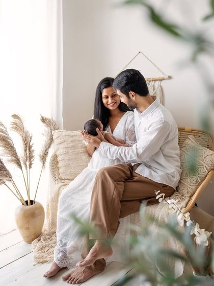 A candid shot of a new family in the studio's boho corner. The natural elements and soft light create a relaxed and warm atmosphere.