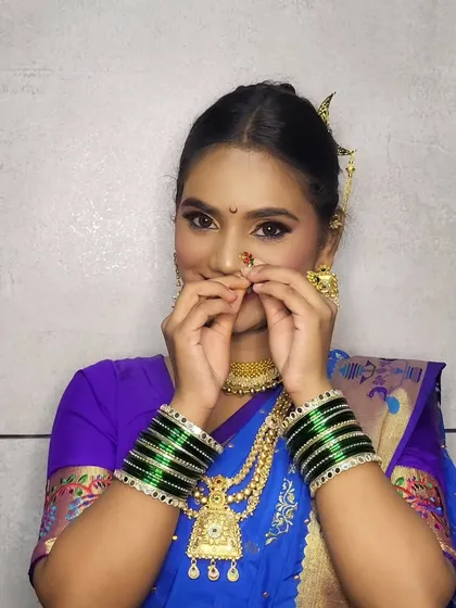 A playful pose adjusting the traditional nose ring, a key element of the Maharashtrian look.
