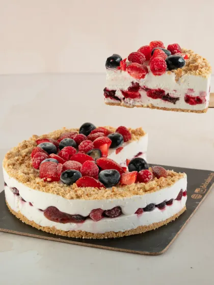 A slice of our Fresh Mixed Berry Cheesecake being lifted, showing the layers of creamy cheesecake and berry compote. It's topped with a beautiful assortment of fresh berries.