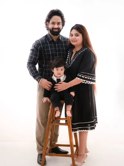 A dapper little gentleman and his parents. This classic family portrait on a high stool showcases the family's style against a clean white background.