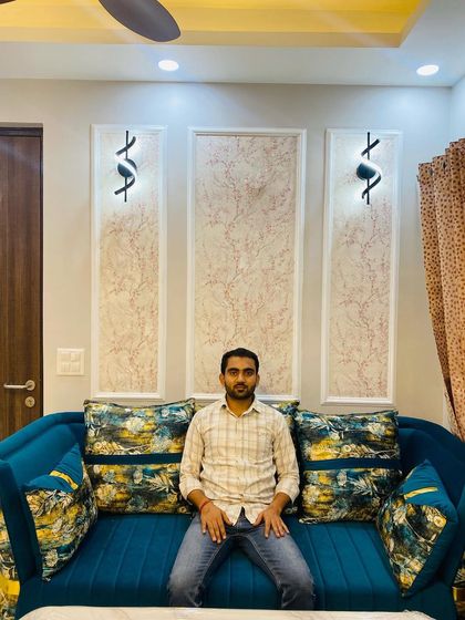 A comfortable seating area I designed. The wall features textured wallpaper within POP moulding frames, flanked by modern wall lights.