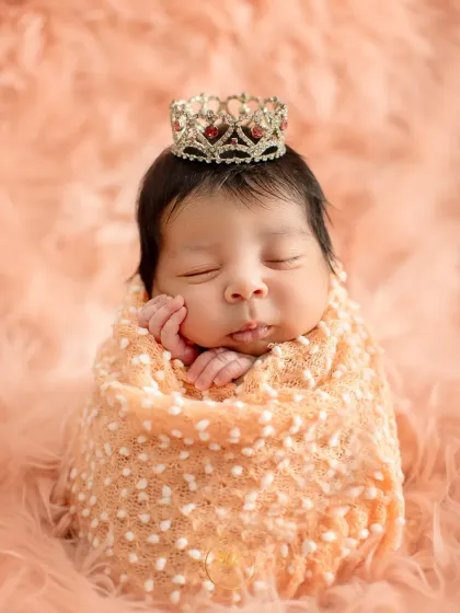 A classic newborn portrait of a sleeping baby girl, swaddled snugly and wearing a tiny, delicate crown. My newborn sessions are always handled with the utmost care and safety for your little one.