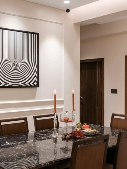 Another angle of the dining space, highlighting the panelled walls and the striking black and white artwork. The warm candlelight adds a soft glow, making the space feel intimate and ready for guests.