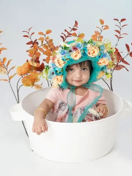 What a shining star! This little girl looks so pretty in her floral bonnet, sitting in a simple white tub.
