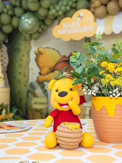 A close-up of a table centerpiece featuring a small Pooh Bear figure with a honey pot, set against a honeycomb-patterned placemat.
