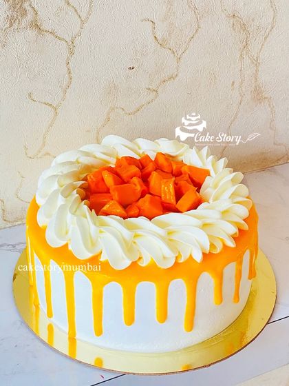 A delicious Alphonso mango cake, perfect for the summer season. This cake features a mango-flavored drip and is topped with fresh, juicy mango chunks.