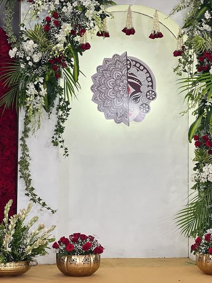 The final executed centerpiece for the 'Mitakshi' theme, beautifully lit and framed by fresh red roses and lush greenery.