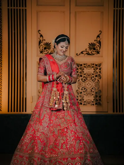 A joyful and candid bridal portrait. We captured this bride's happy smile as she looks down, showcasing the intricate details of her lehenga and kalire.
