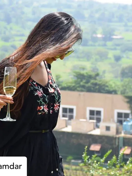 A guest enjoys a glass of our sparkling wine while overlooking the scenic expanse of our Nashik vineyard. The tour offers a chance to sip and stroll, immersing yourself in the beautiful landscape where our grapes mature.