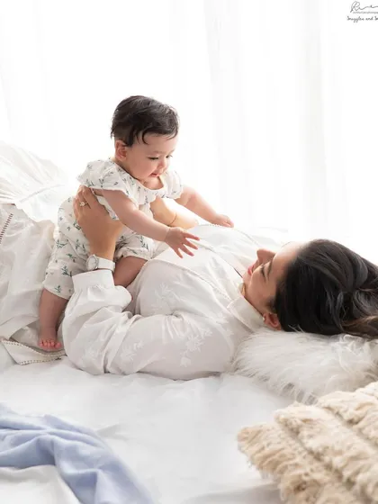 Playful moments between mother and baby on the bed. The natural light and relaxed setting create a beautiful, lifestyle feel.