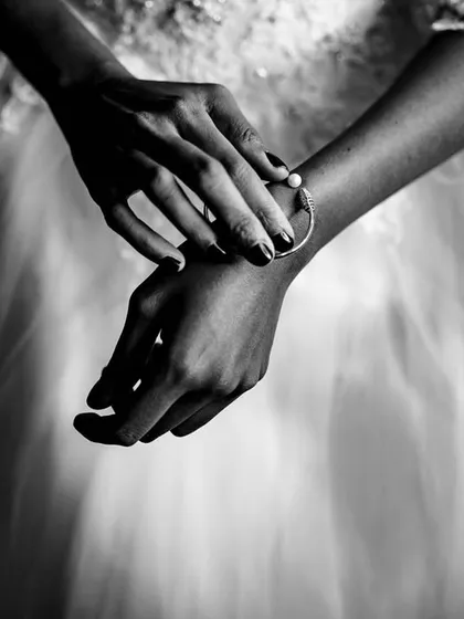 The beauty is in the details. This close-up, black and white shot focuses on the bride's hands and bracelet, a small but significant part of her wedding day look.