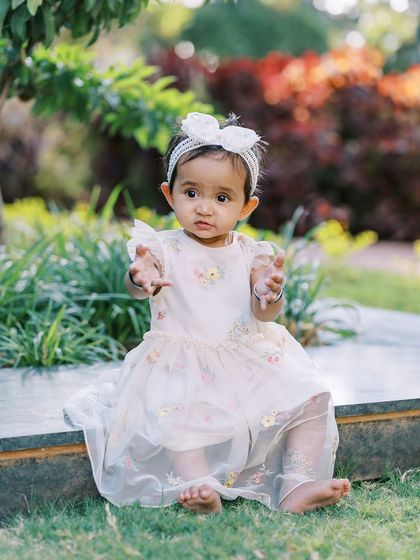 A beautiful outdoor portrait of a one-year-old girl, sitting on a bench. The natural setting and soft light are perfect for capturing her sweet personality.