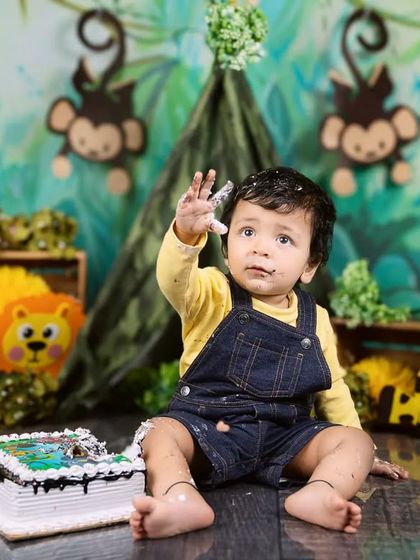 With a frosting-covered hand held high, this baby boy is declaring his cake smash a success!