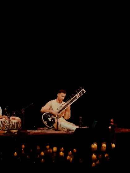 The full band on stage in Chandigarh, surrounded by candles. Even in a larger ensemble, the atmosphere remains intimate and focused on the music's healing qualities.