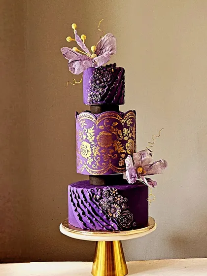 Inspired by the timeless beauty of a Banarasi saree, this three-tiered anniversary cake is a tribute to Indian artistry. The design features deep purple fondant with intricate gold stenciling, monochrome ruffles, and delicate wafer paper flowers. It’s a luxurious and unique creation for a truly special celebration.