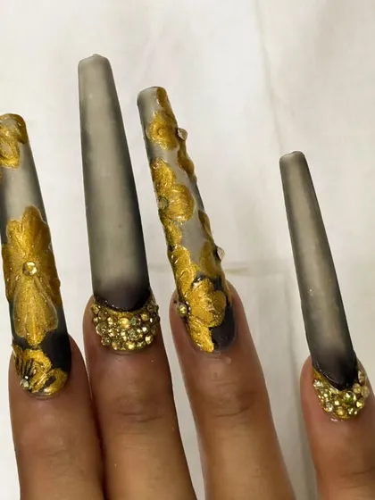 A different perspective of the matte grey and gold leaf nails, showcasing the length and the contrast between the matte finish and the metallic gold.