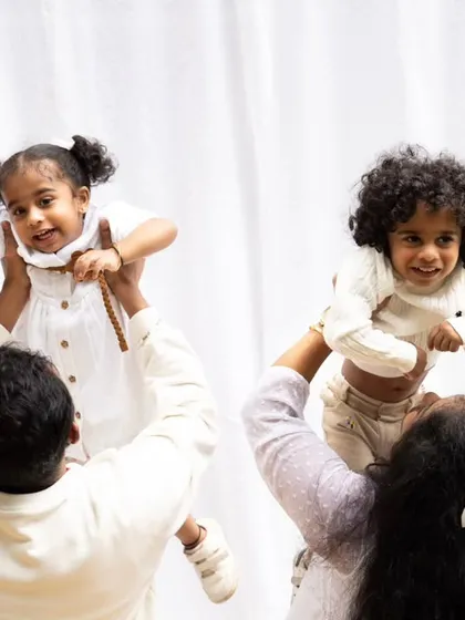 A playful outdoor shot of parents lifting their two children in the air. This photo is full of energy and captures the pure joy of family fun.