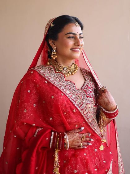 A beautiful sunlit portrait of a bride in red, showcasing a flawless base and defined eyes.
