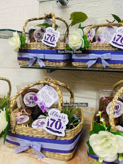 A collection of the 70th birthday hampers, each adorned with a "Cheers to 70" cutout and a white rose.