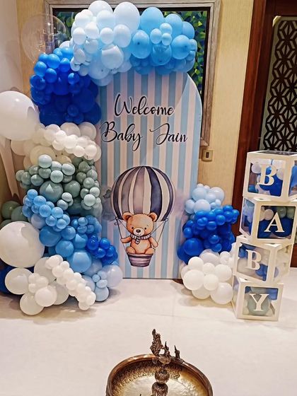 A "Welcome Baby Jain" decoration with a hot air balloon theme, featuring blue and white balloons and transparent "BABY" display boxes.