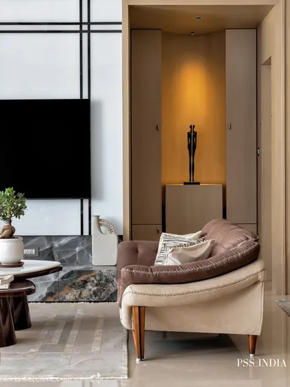 A detail shot focusing on a cozy corner. The two-toned sofa is complemented by a sculptural art piece in an illuminated niche, demonstrating how to use lighting to highlight decor.