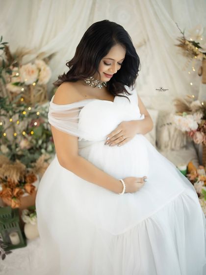 A beautiful portrait of a mother-to-be holding a white heart-shaped pillow. This simple prop adds a touch of sweetness to the all-white theme.