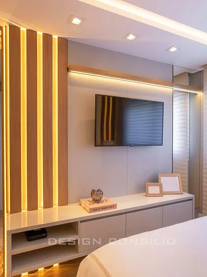 This TV unit design incorporates vertical wooden slats with hidden lighting. It adds texture and warmth to the bedroom while providing ample storage in the console below.