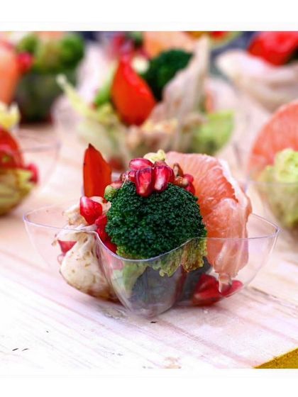 A close up of a single salad cup, highlighting the fresh ingredients like broccoli, grapefruit, and pomegranate seeds. We focus on quality and freshness in every component of our dishes.