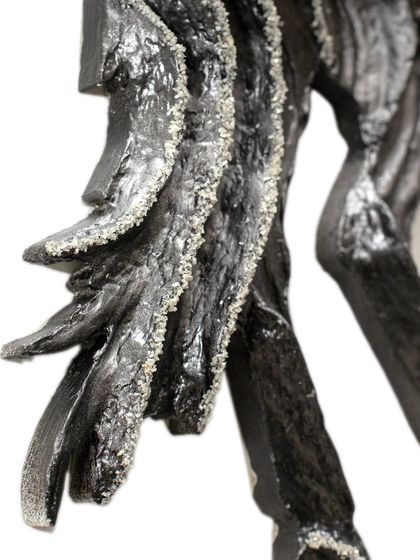 A close-up of the leg and body, showing the raw, powerful texture of the sculpture.