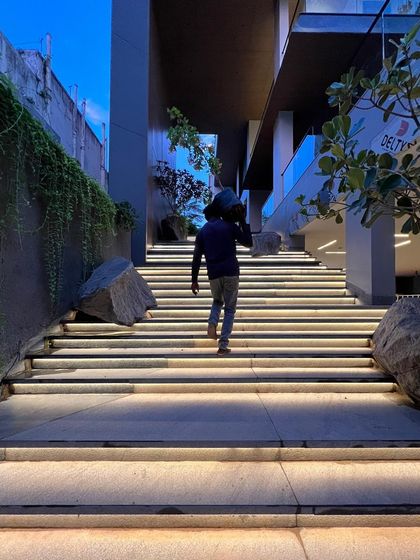 A candid shot of a worker on a site at dusk, carrying materials up a flight of illuminated stairs. This image captures the quiet progress and hard work that goes into every project.
