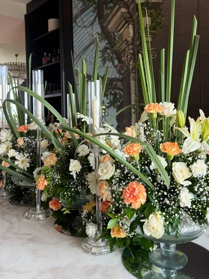 The beauty is in the details. Our tablescapes are designed to be a feast for the eyes, combining fresh flowers like carnations and lilies with tall, elegant candles to create a warm and inviting atmosphere for your guests.
