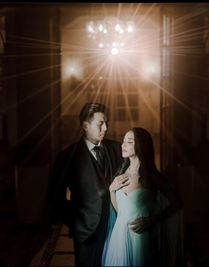 A dramatic night shot with a starburst light effect. The makeup is glamorous and designed to catch the light, creating a magical and cinematic feel.