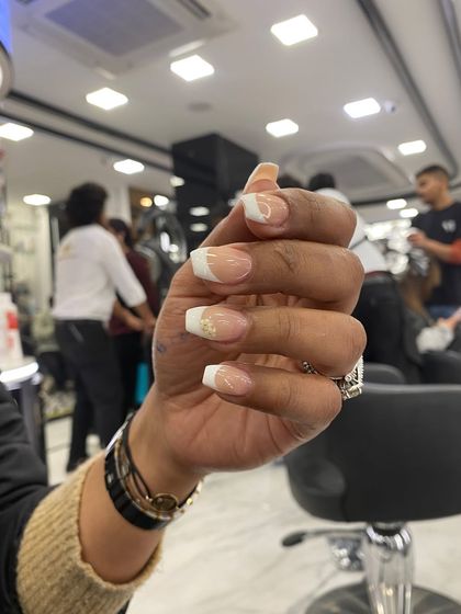 A classic French manicure on square-shaped nails with a subtle touch of gold glitter on the smile line for a bit of sparkle.