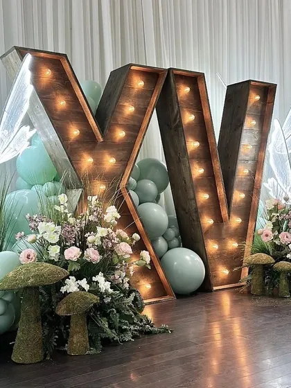 Large, rustic marquee letters filled with balloons add a personalized and stylish touch to the decor, perfect for displaying initials or age.