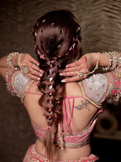 Channeling a Bollywood diva vibe with this intricate mehendi braid. The tiny mirrors woven into the hair catch the light beautifully and add a playful, glamorous touch.