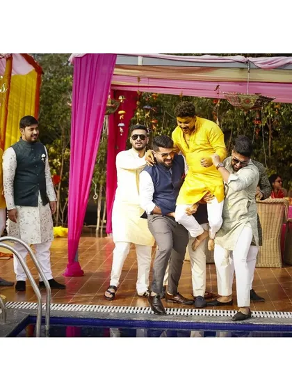 The moment before the splash. The groom's friends carrying him towards the pool is a classic Haldi tradition, full of anticipation and fun.