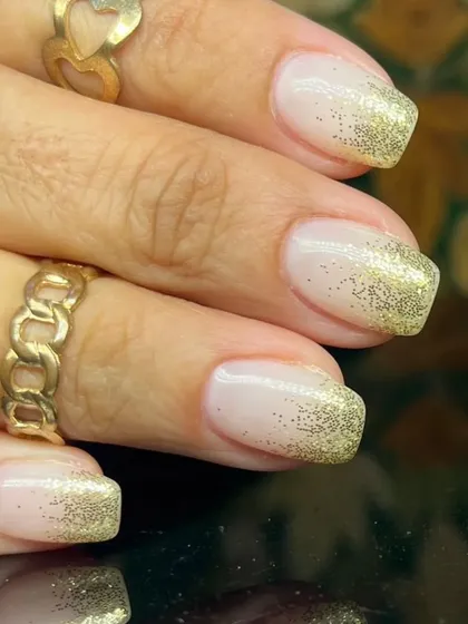 A classic French manicure with a twist, featuring a beautiful gold glitter fade from the tips.
